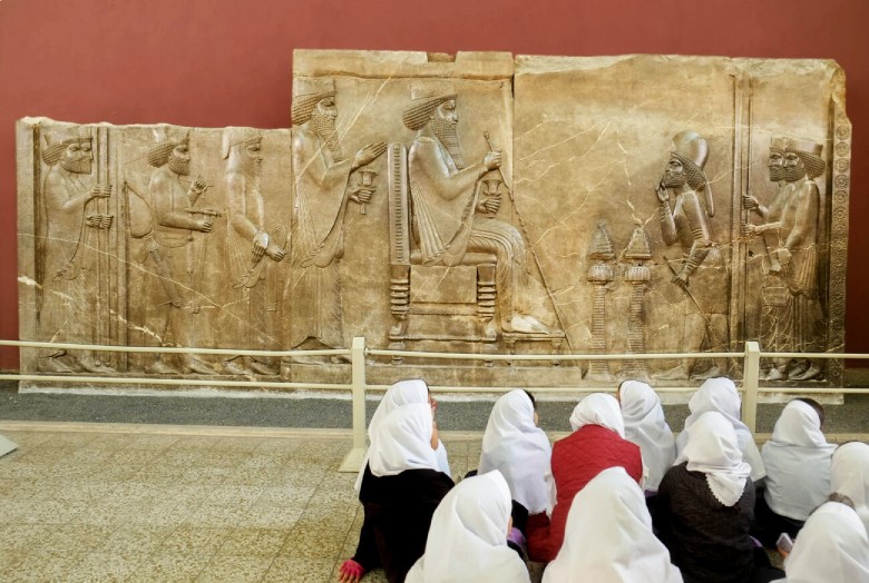 School girls attending history in front of the Persepolis Bas-Relief of King Darius at the National Museum of Iran