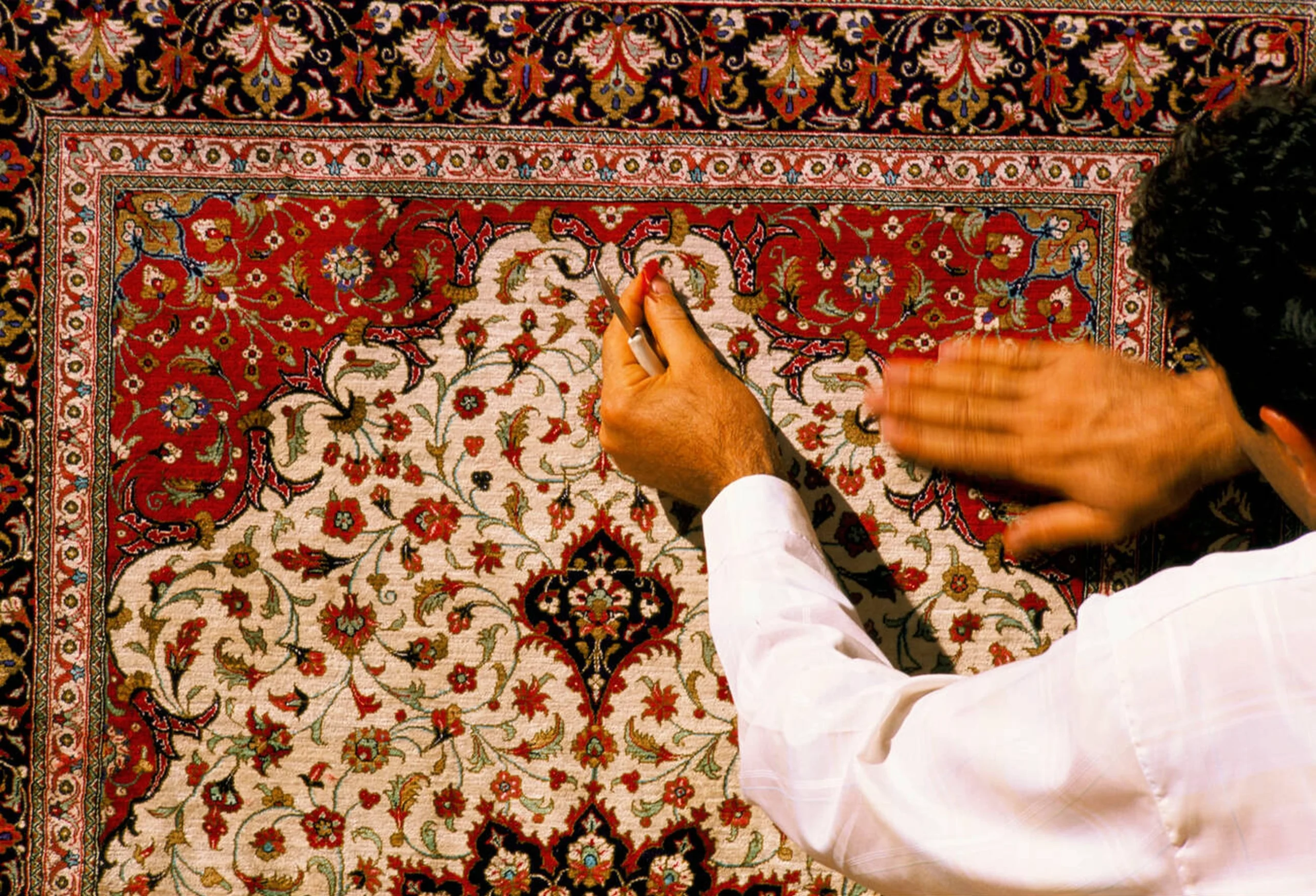 A Skilled Artisan Meticulously Weaves A Persian Carpet In Qom, Iran, Showcasing The Intricate Craftsmanship Behind This Centuries-Old Tradition. When It Comes To Shipping Persian Carpets, The Artistry And Delicate Materials Require Careful Handling To Ensure Their Safe Arrival At International Destinations.