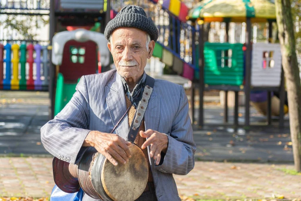 Elderly Musician Playing Tombak In The Park